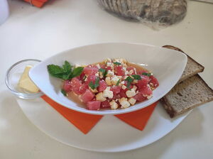 Wassermelonen-Fetakäse-Salat mit frischer Minze und Vollkornbrot am Tisch im Café Ritter von Böhl.