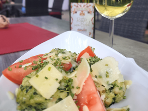 Frischer Salat mit Tomaten, Kräutern und Käse, serviert im Cafe Ritter von Böhl, neben einem Glas Wein.